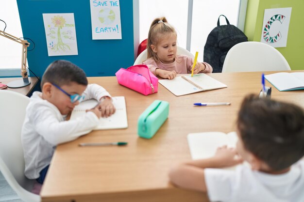 Group of kids students sitting on table drawing on notebook at classroom