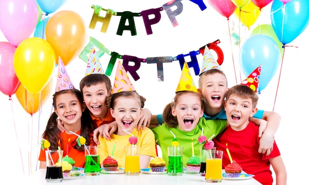 Gruppo di bambini che ridono divertendosi alla festa di compleanno - isolato su un bianco.