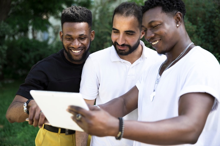 Free Photo group of male friends looking at a device  