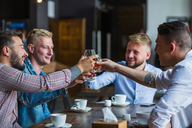 飲み物の眼鏡を焼くレストランに座っている男性の友人のグループ