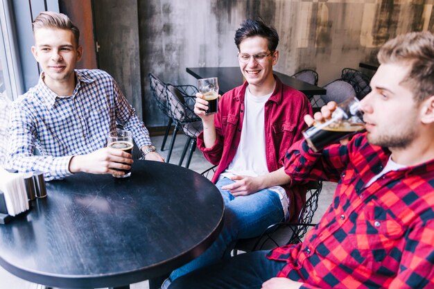 Foto gratuita gruppo di amici maschi seduti insieme a tavola godendo la birra nel ristorante bar