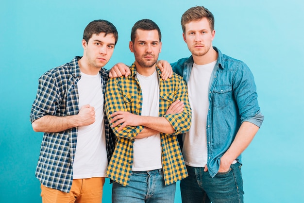 Group of a male friends standing against blue background