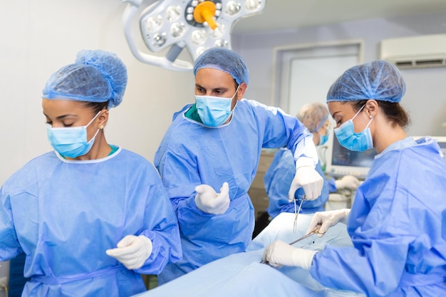 Foto gratuita gruppo di equipe medica che esegue urgentemente un intervento chirurgico e aiuta il paziente in sala operatoria in ospedale team medico che esegue un intervento chirurgico in una sala operatoria moderna e luminosa