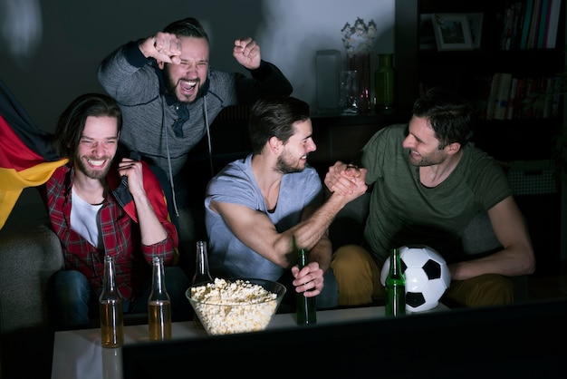 Group of men drinking beer and watching soccer on TV