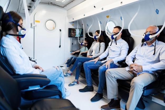 Free photo group of mixed age people wearing masks while having oxygen therapy in hyperbaric chamber