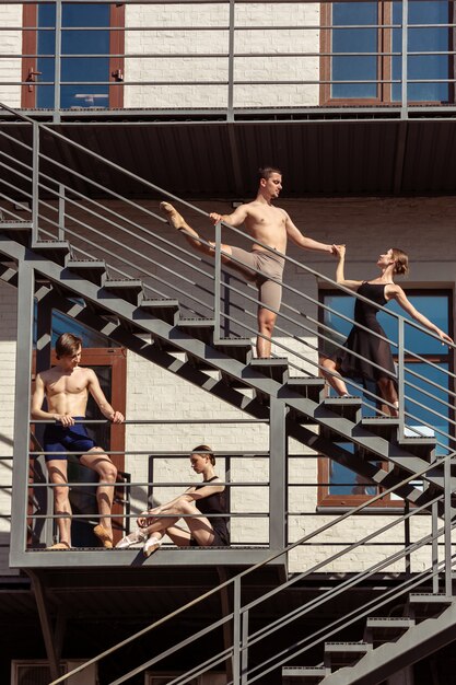 The group of modern ballet dancers performing on the stairs at the city