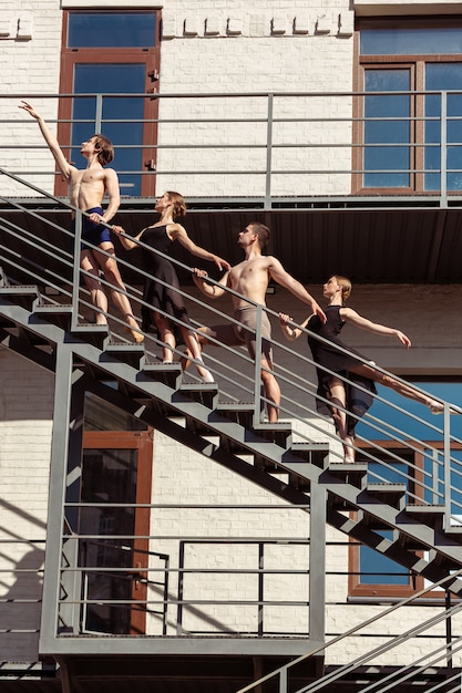 The group of modern ballet dancers performing on the stairs at the city