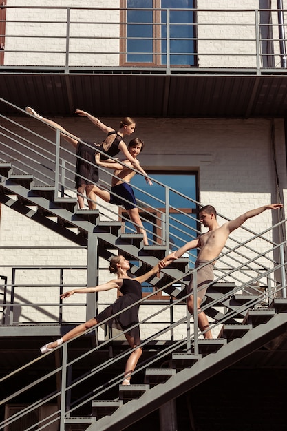 The group of modern ballet dancers performing on the stairs at the city