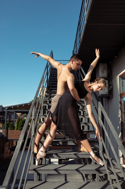 The group of modern ballet dancers performing on the stairs at the city