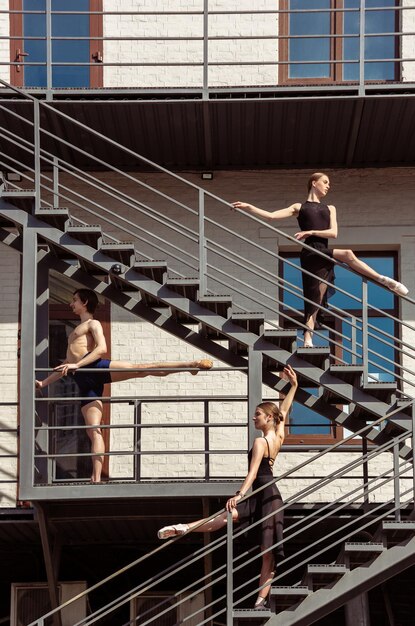 The group of modern ballet dancers performing on the stairs at the city