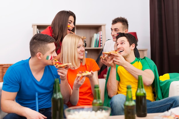 축구 경기 휴식 시간 동안 피자를 먹는 다국적 사람들의 그룹