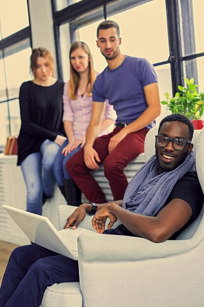 Group of multiracial students using with a laptop. Filtered warm toned image.