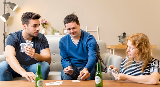 Бесплатное фото Группа друзей с пивом и игрой в карты дома