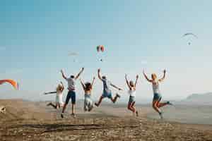 무료 사진 언덕 위에 점프하는 친구의 그룹