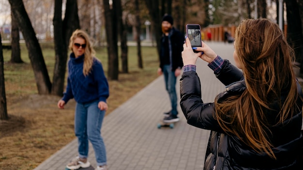 무료 사진 여자가 사진을 찍는 동안 공원에서 스케이트 보드 친구 그룹