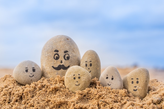砂​に​描かれた​顔​を​持つ​石​の​グループ​。​父​と​彼​の​子供たち​。​幸せな​父​の​日​の​コンセプト​カード​。