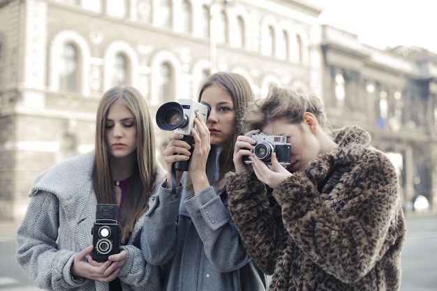 Бесплатное фото Группа из трех подруг, делающих фотографии на свои камеры