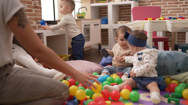 Бесплатное фото Группа малышей, играющих с игрушками, сидящими на полу в детском саду