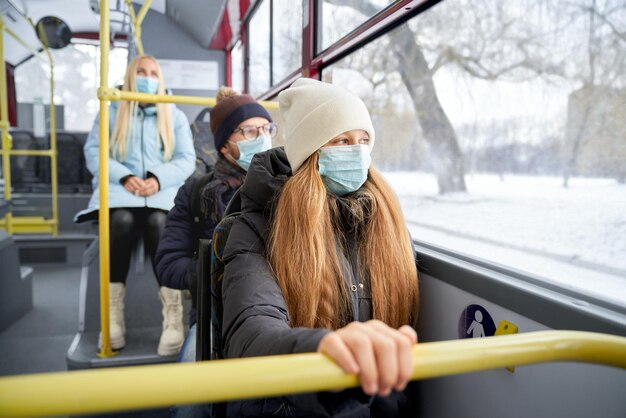 保護マスクを着用してバスに座っている公共交通機関で旅行する乗客のグループ