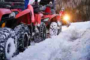 Free photo group of people driving quad bikes on snowy road