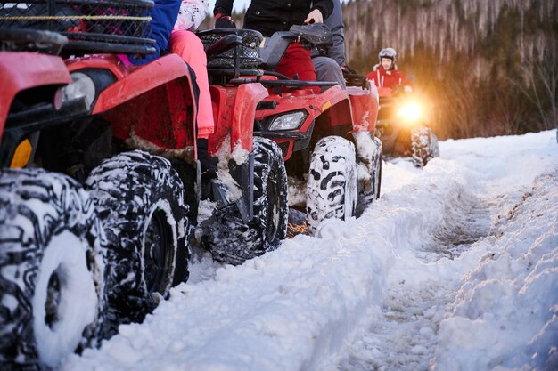 Group of people driving quad bikes on snowy road