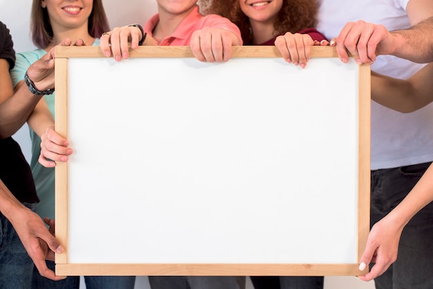 Group of people holding blank white picture frame with wooden boarder