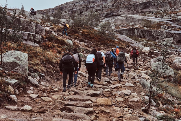 사람들의 그룹이 노르웨이 산에서 하이킹을 하고 있습니다. 배낭을 메고 산에서 추적하는 등산객 그룹.