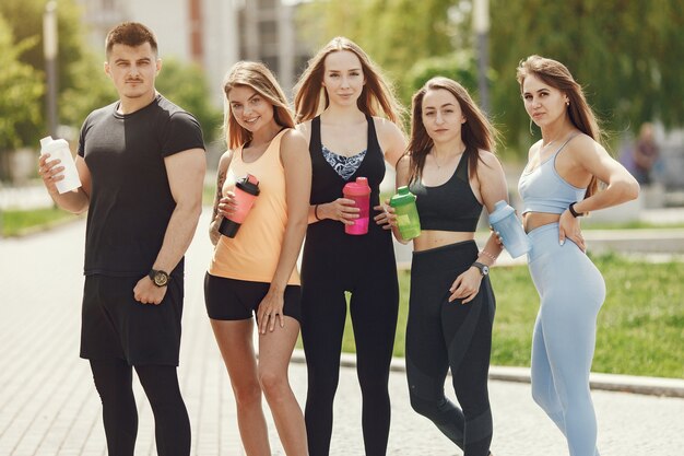 Group of people in a park. Boy with four girls. Sports people with bottls of water.