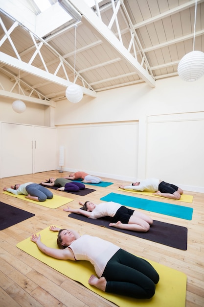 Free photo group of people performing supta virasana on exercise mat