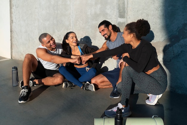 Free photo group of people putting their hands together while exercising outdoors