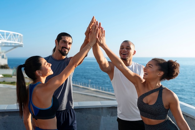 group of people putting their hands together while exercising outdoors