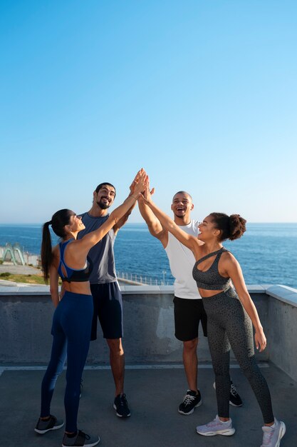 Group of people putting their hands together while exercising outdoors