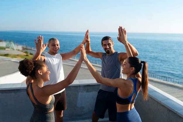 group of people putting their hands together while exercising outdoors