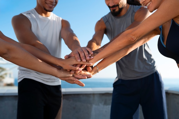 Group of people putting their hands together while exercising outdoors