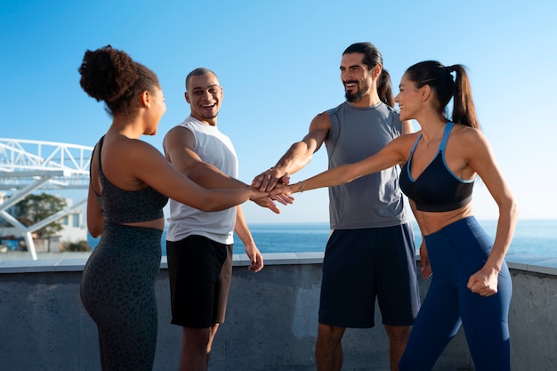 Group of people putting their hands together while exercising outdoors