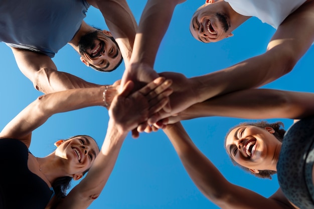 Group of people putting their hands together while exercising outdoors