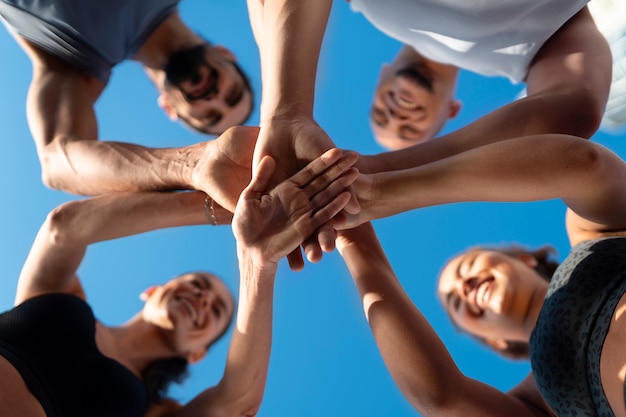 group of people putting their hands together while exercising outdoors