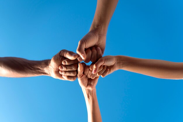 group of people putting their hands together while exercising outdoors