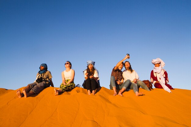 Группа людей, сидящих на вершине дюны