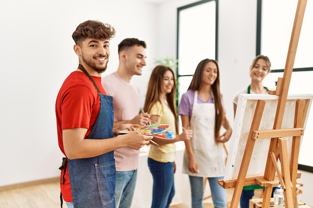 Group of people smiling happy drawing on canvas standing at art studio.