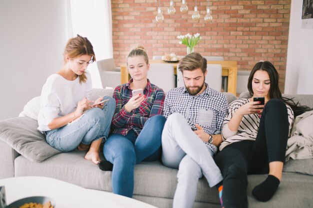 Group of people using gadgets on sofa