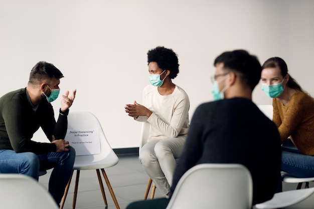 Group of people wearing protective face masks while talking during psychotherapy meeting