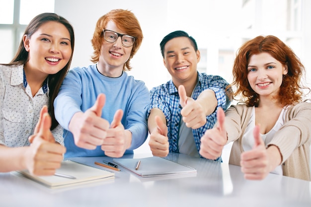 Group of satisfied students showing thumbs up