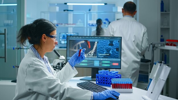 테스트 튜브 및 과학 기기에서 생화학 샘플을 검사하는 동안 실험실에서 작업하는 실험실 코트를 입고 과학자 그룹