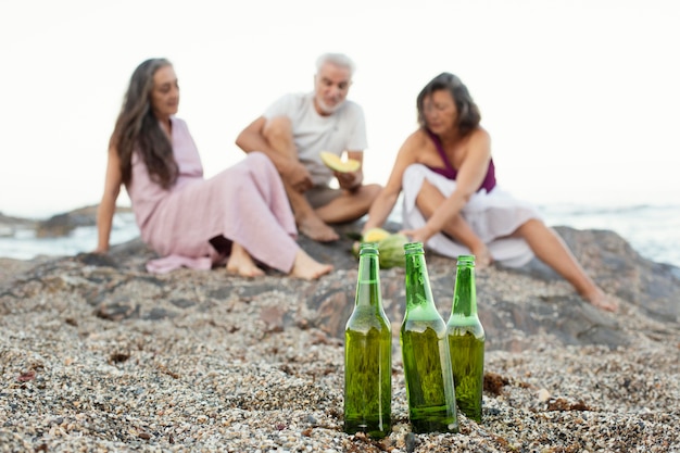 Group of senior friends having beers on the beach