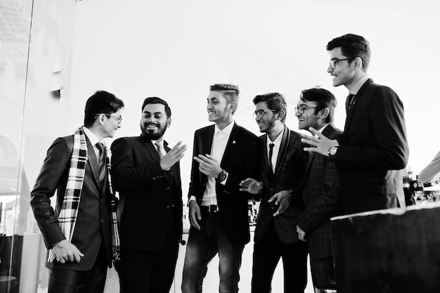 カフェに立って何かを話し合うスーツを着た6人のインド人ビジネスマンのグループ