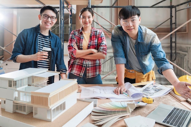 건설 엔지니어와 컨설팅하는 똑똑한 아시아 건축가 인테리어 디자인 팀 그룹은 주택 개조 구조 배경에서 주택 프로젝트 청사진 및 주택 모형과 함께 브레인스트롬 회의를 진행합니다.
