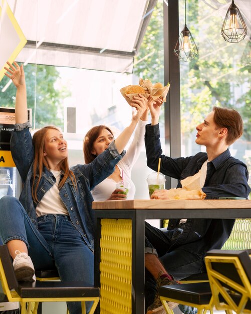 Group of smiley friends toasting with burgers