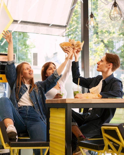 ハンバーガーで乾杯する笑顔の友達のグループ