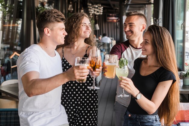 Group of smiling friends holding alcohol drinks set making toast